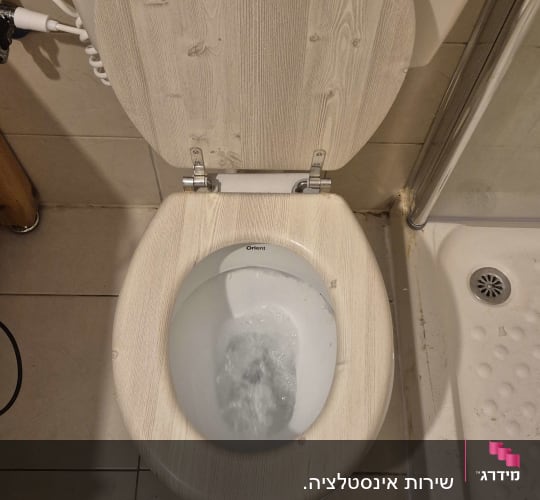 אסלה עם מכסה עץ ומים זורמים